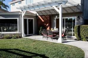 A covered patio with a table and chairs, a brick wall, and a glass door leading to a garage.