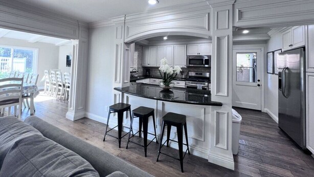 A modern kitchen with white cabinetry, a black countertop, and stainless steel appliances. - Sensational 6 Bedroom 4 Bathroom Pool Home (3 Master Bedrooms W/bathrooms) (Anaheim)