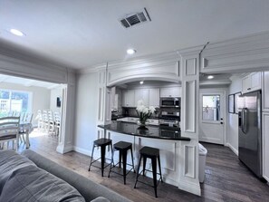 A modern kitchen with white cabinetry, a black countertop, and stainless steel appliances.