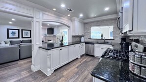 A modern kitchen with white cabinetry, a black granite countertop, and a stainless steel range hood. - Sensational 6 Bedroom 4 Bathroom Pool Home (3 Master Bedrooms W/bathrooms) (Anaheim)