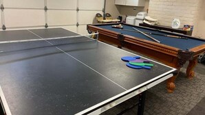 A billiards table with a pool cue and balls, a white cabinet, and a brick wall. - Fantastic 5 Bedroom 4 Bath Home With new Pool & Jacuzzi (Anaheim)