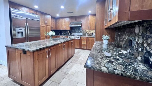 A modern kitchen with wooden cabinets, granite countertops, and a built-in island. - Fantastic 5 Bedroom 4 Bath Home With new Pool & Jacuzzi (Anaheim)