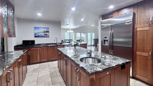 A spacious kitchen with a granite countertop, stainless steel appliances, and wooden cabinets. - Fantastic 5 Bedroom 4 Bath Home With new Pool & Jacuzzi (Anaheim)