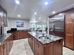 A spacious kitchen with a granite countertop, stainless steel appliances, and wooden cabinets. - Fantastic 5 Bedroom 4 Bath Home With new Pool & Jacuzzi (Anaheim)