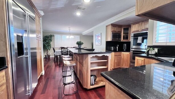 A modern kitchen with wooden cabinets, stainless steel appliances, and a bar area. - Amazing Large Family Home W/pool, 1 Mile to Disney (Anaheim)