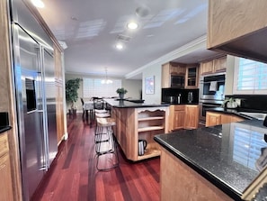 A modern kitchen with wooden cabinets, stainless steel appliances, and a bar area.
