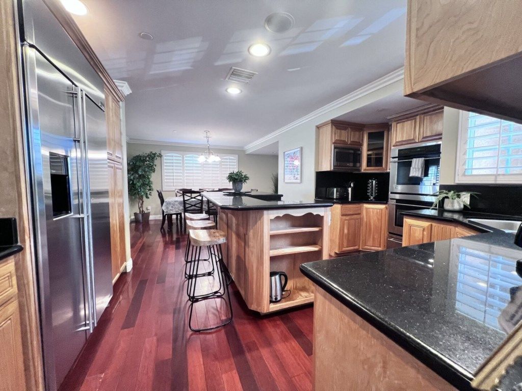 A modern kitchen with wooden cabinets, stainless steel appliances, and a bar area.