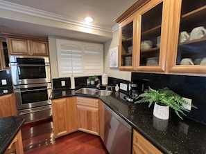 A kitchen with wooden cabinets, stainless steel appliances, a black countertop, and a potted plant. - Amazing Large Family Home W/pool, 1 Mile to Disney (Anaheim)