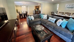 A living room with a sectional sofa, a coffee table, and a dining area with a table and chairs. - Amazing Large Family Home W/pool, 1 Mile to Disney (Anaheim)