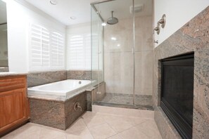 A bathroom with a bathtub, shower, and fireplace.