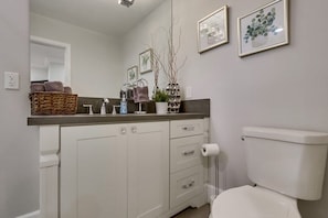 Un baño con inodoro, lavamanos, espejo y toallero.