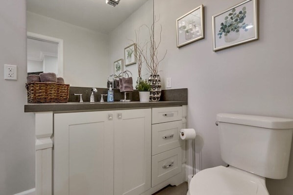 A bathroom with a toilet, a sink, a mirror, and a towel rack. - 5 Bedroom plus loft room, 3 Bath home (Fullerton)