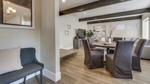 Un salon moderne comprenant un canapé, des fauteuils, une table à manger et un grand miroir.