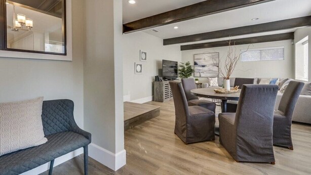 A modern living room with a sofa, chairs, a dining table, and a large mirror. - 5 Bedroom plus loft room, 3 Bath home (Fullerton)