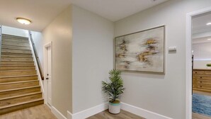 A hallway with a wooden staircase, a potted plant, and a framed abstract painting on the wall. - 5 Bedroom plus loft room, 3 Bath home (Fullerton)