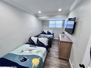 A bedroom with two beds, a TV mounted on the wall, and a small cabinet. - 5 Bedroom plus loft room, 3 Bath home (Fullerton)