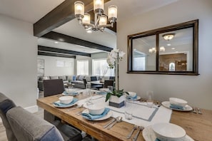 A dining area with a wooden table set for four, a chandelier, and a large mirror on the wall. - 5 Bedroom plus loft room, 3 Bath home (Fullerton)