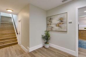 A hallway with a wooden staircase, a potted plant, and a framed abstract painting on the wall. - 5 Bedroom plus loft room, 3 Bath home (Fullerton)