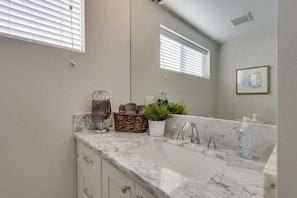 A bathroom with a marble sink, towel rack, wicker basket, potted plant, and a framed picture on the wall. - 5 Bedroom plus loft room, 3 Bath home (Fullerton)