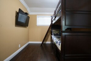 A room with a bunk bed, a television mounted on the wall, and a window with blinds. - Dazzling 5 Bedroom Pool Home 1/4 Mile To Disney (Anaheim)
