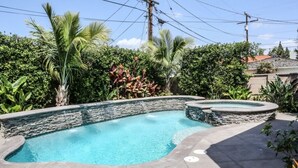 A swimming pool with a stone wall, surrounded by lush greenery and a clear sky. - Awesome Pool Home 1/4 Mile To Disney Tram on Magic Way (Anaheim)