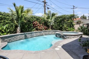 A swimming pool with a stone wall, surrounded by lush greenery and a clear sky. - Awesome Pool Home 1/4 Mile To Disney Tram on Magic Way (Anaheim)