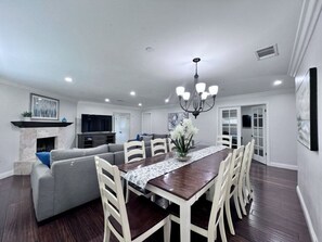 A spacious living room with a dining area, a fireplace, and a chandelier. - Awesome Pool Home 1/4 Mile To Disney Tram on Magic Way (Anaheim)