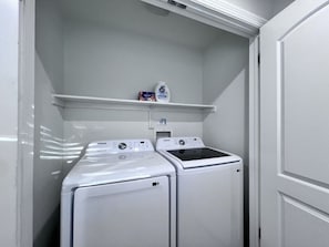 A laundry room with two front-loading washers and dryers, a shelf with detergent, and a control panel. - Awesome Pool Home 1/4 Mile To Disney Tram on Magic Way (Anaheim)