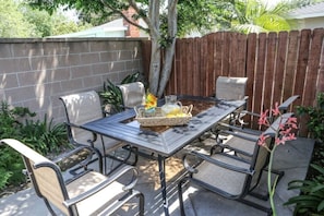 A patio with a metal table, four chairs, and a small decorative plant.