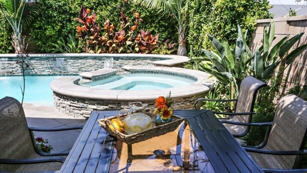A pool area with a hot tub, outdoor seating, and a table with a beverage tray. - Awesome Pool Home 1/4 Mile To Disney Tram on Magic Way (Anaheim)