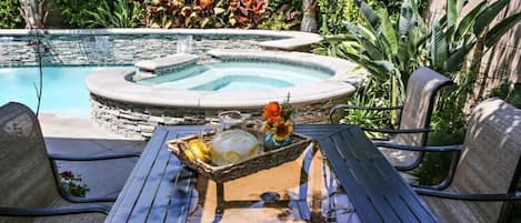 A pool area with a hot tub, outdoor seating, and a table with a beverage tray.