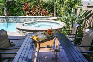 A pool area with a hot tub, outdoor seating, and a table with a beverage tray. - Awesome Pool Home 1/4 Mile To Disney Tram on Magic Way (Anaheim)