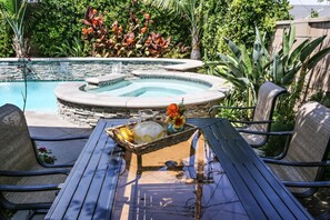 A pool area with a hot tub, outdoor seating, and a table with a beverage tray. - Awesome Pool Home 1/4 Mile To Disney Tram on Magic Way (Anaheim)