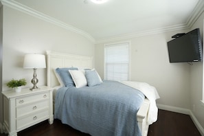 A bedroom with a bed, a nightstand, a lamp, a TV, and a window with blinds. - Awesome Pool Home 1/4 Mile To Disney Tram on Magic Way (Anaheim)