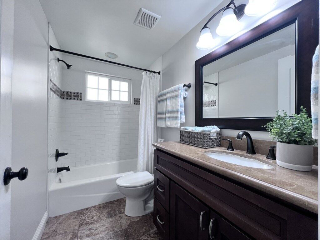 A bathroom with a bathtub, toilet, sink, and a large mirror.