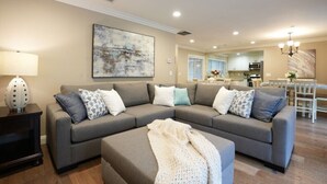 A living room with a grey sectional sofa, a coffee table, and a lamp. - Fantastic 6 bedroom, 4.5 bath home (4 master Suites), pool home (Anaheim)