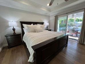 Un dormitorio con una cama grande, dos mesitas de noche y vistas a un patio exterior.