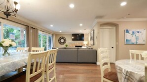 A dining area with a marble table, wooden chairs, a gray sofa, and a clock on the wall. - Fantastic 6 bedroom, 4.5 bath home (4 master Suites), pool home (Anaheim)
