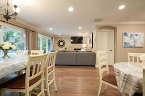 A dining area with a marble table, wooden chairs, a gray sofa, and a clock on the wall. - Fantastic 6 bedroom, 4.5 bath home (4 master Suites), pool home (Anaheim)