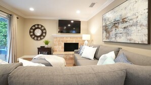 A living room with a fireplace, a clock, and a large abstract painting. - Fantastic 6 bedroom, 4.5 bath home (4 master Suites), pool home (Anaheim)