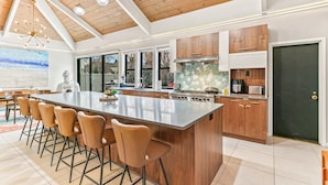 Cozinha moderna com uma ilha grande, armários de madeira e área de jantar com banquetas.