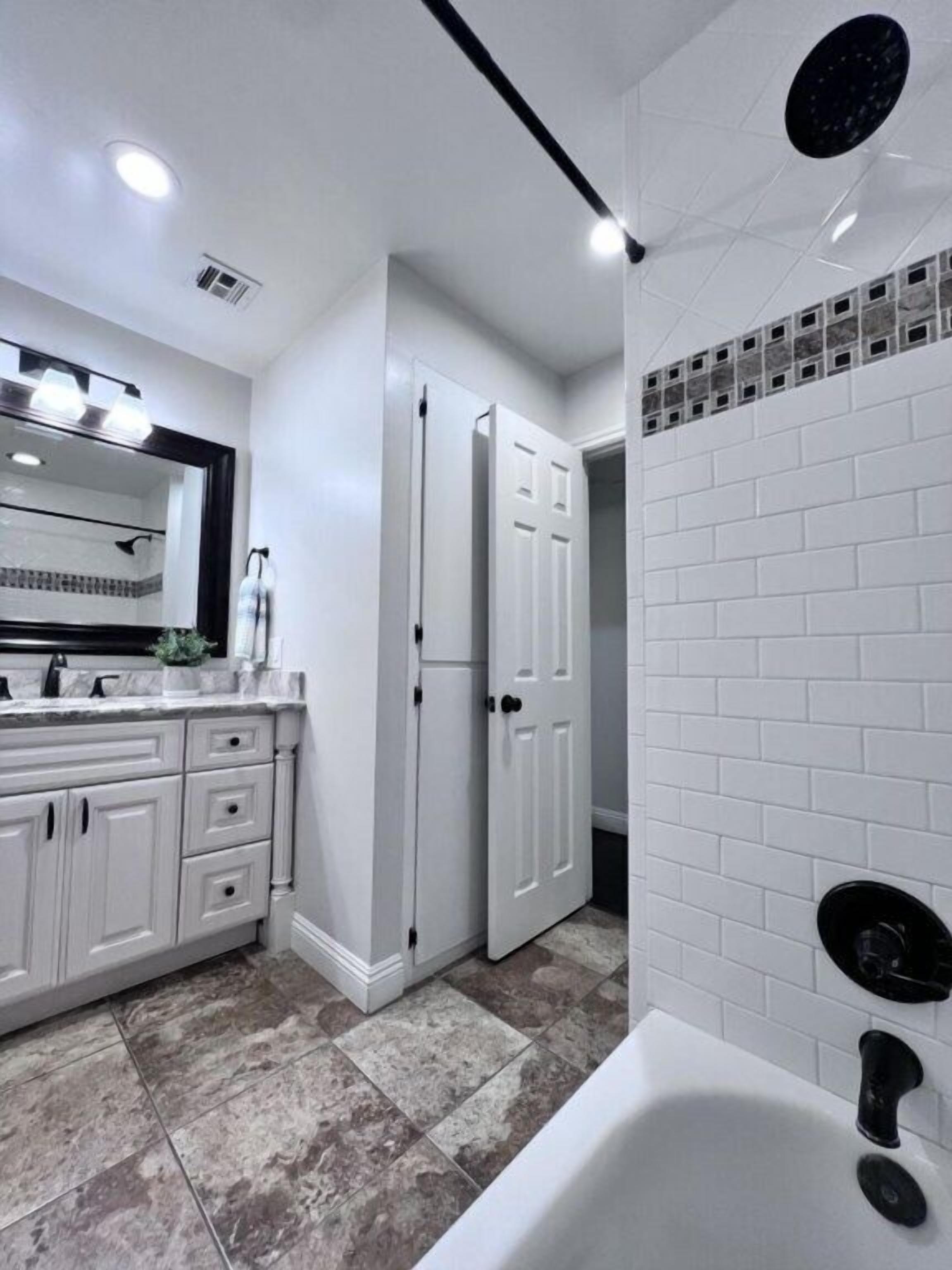 A bathroom with a white vanity, a bathtub, and a shower area.