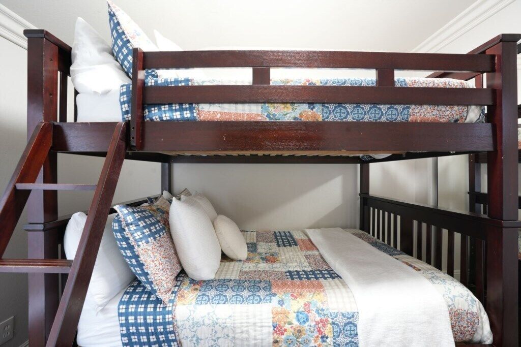A bunk bed with a ladder, pillows, and a quilt.