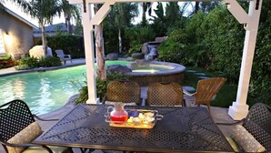 Eine Terrasse im Freien mit Pool, Stühlen und einem Tisch mit Getränkeablage.