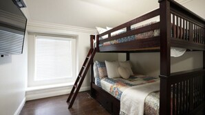 Ein Stockbett mit einer Leiter, ein Fenster mit Jalousien und ein Holzboden.