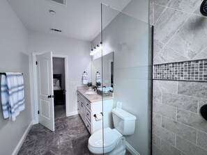 A bathroom with a glass shower enclosure, a toilet, and a vanity with a mirror. - Incredible 5 Bedroom, 4 Bath, Rock Pool & Jacuzzi Home, 1/2 Mile Walk To Disney (Anaheim)