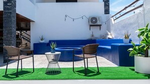 A rooftop patio with a blue sofa, two wicker chairs, a small round table, and potted plants. - Casa Arrecife| Tortuga: Wifi+ Cozy, Private bathroom, 1 room (La Ventana)
