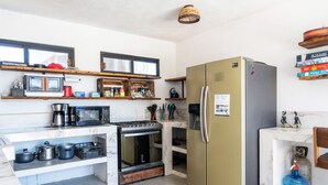 A compact kitchen with a stove, microwave, and refrigerator. Shelves above the counter hold various kitchen items. - Casa Arrecife| Tortuga: Wifi+ Cozy, Private bathroom, 1 room (La Ventana)