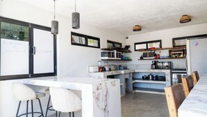 A modern kitchen with a marble island, bar stools, and a dining area. - Casa Arrecife| Tortuga: Wifi+ Cozy, Private bathroom, 1 room (La Ventana)