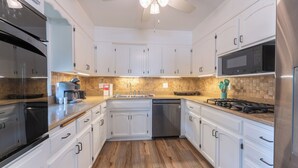Una cocina moderna con armarios blancos, un refrigerador de acero inoxidable, un microondas y una cafetera.